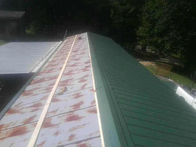Old rusted panels beside newly installed green metal roofing — Wind Damage Roof Repair by Roofing Brothers in Eutawville