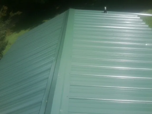 New green metal panels meeting at the ridge of a roof — Flat Roof Repair work by our crew in Eutawville
